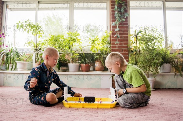 Caucasian brothers playing game on floor