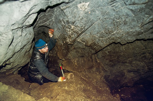 Caucasian climber exploring rock cave