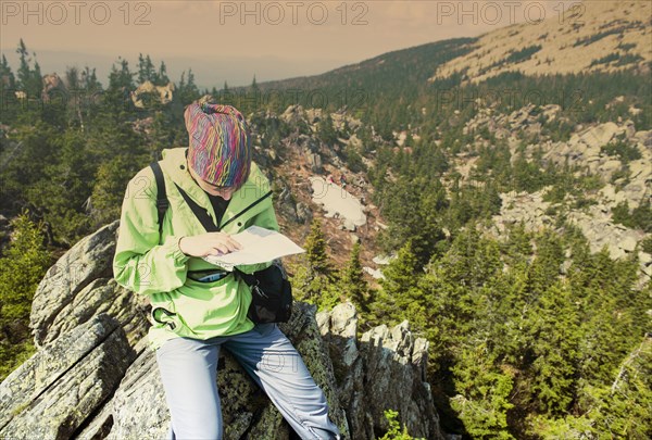 Caucasian hiker reading map on hilltop