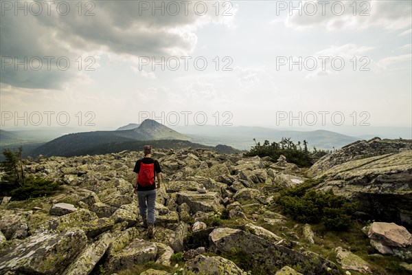 Caucasian hiker walking in rocky field in remote landscape