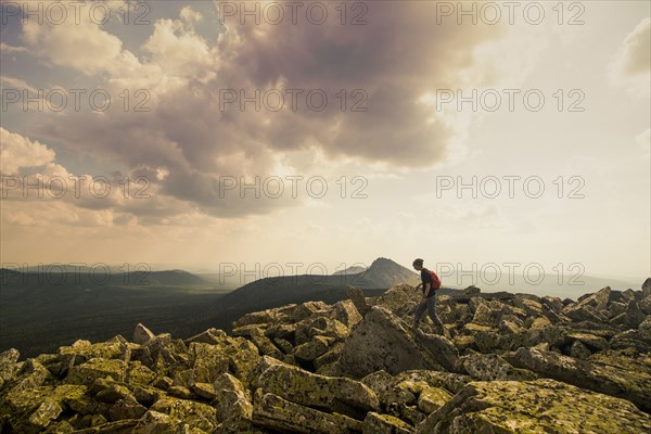 Caucasian hiker walking in rocky field in remote landscape