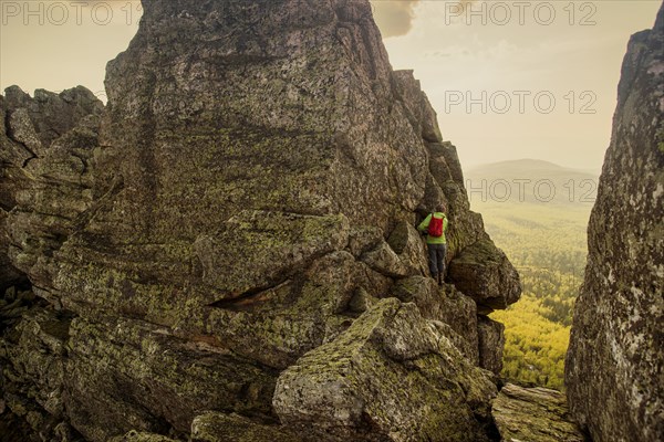 Caucasian hiker climbing on rock formation