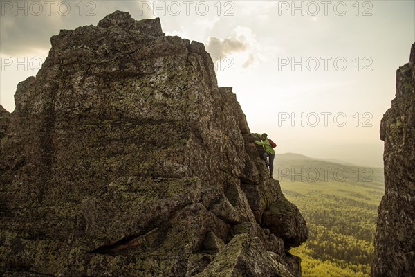 Caucasian hiker climbing on rock formation