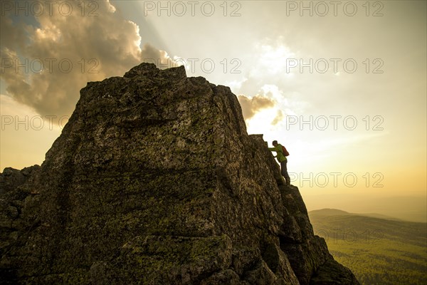 Caucasian hiker climbing on rock formation