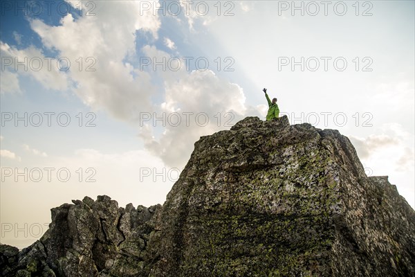 Caucasian hiker cheering on rocky hilltop