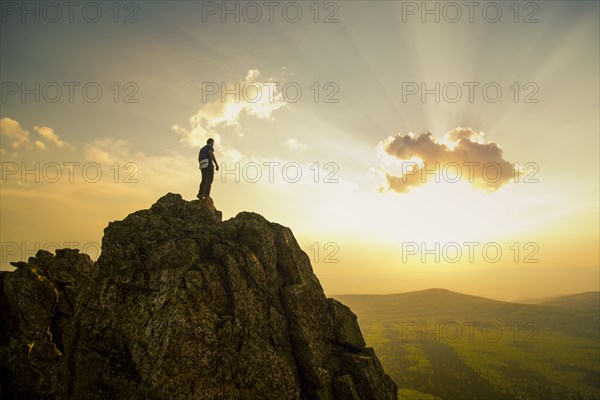 Caucasian hiker on rocky hilltop in remote landscape