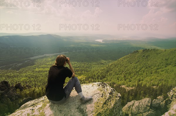 Caucasian hiker admiring remote landscape from rocky hilltop