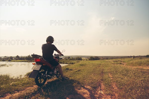 Caucasian man riding motorcycle in rural field