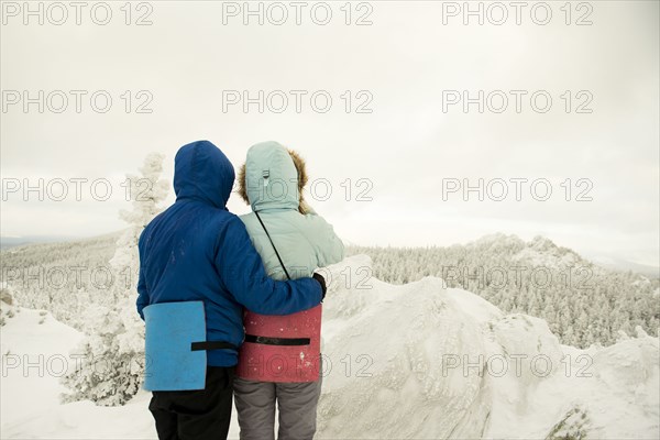 Caucasian hikers on mountaintop admiring snowy landscape