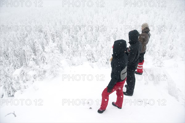 Caucasian hikers on mountaintop admiring snowy forest