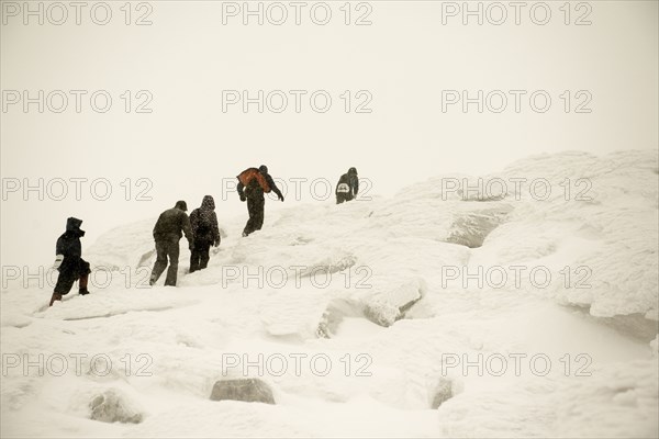 Caucasian hikers climbing snowy mountain