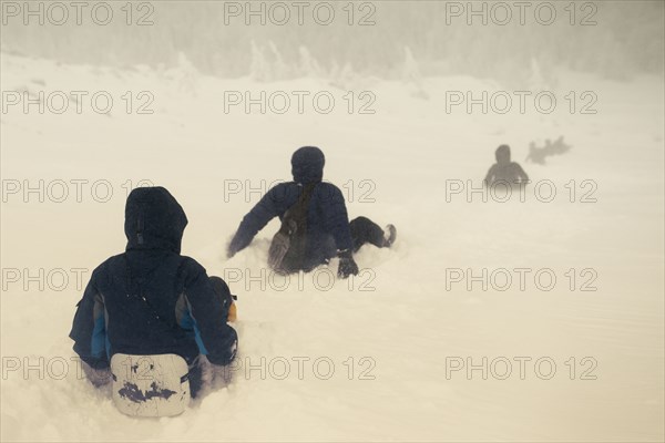 Caucasian hikers sledding on snowy hill