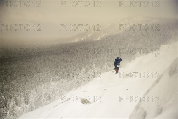 Caucasian hiker waking on snowy hillside