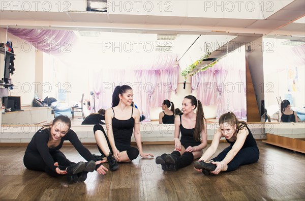 Caucasian dancers stretching in studio