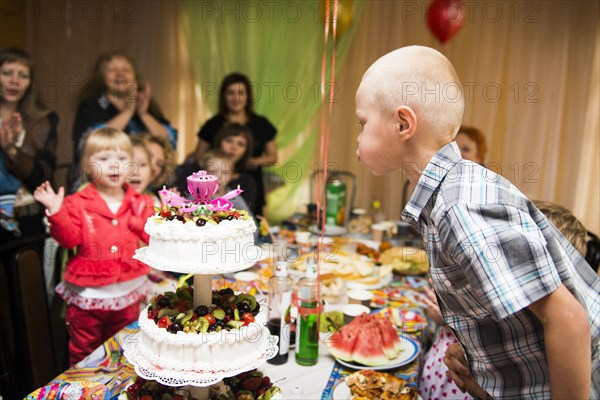 Caucasian boy blowing candles on birthday cake