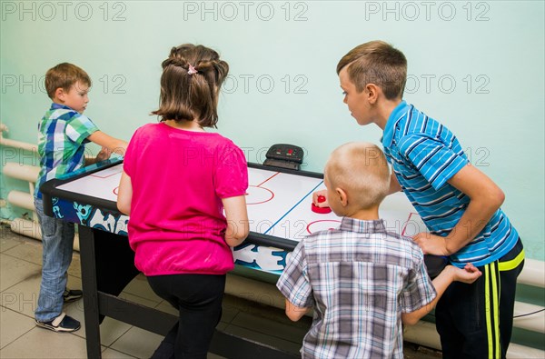 Caucasian children playing air hockey