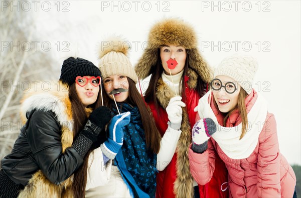 Caucasian girls playing with disguises in snow