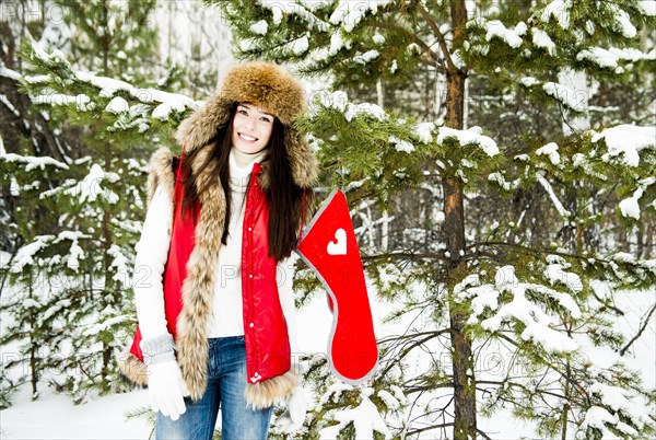 Caucasian girl hanging Christmas stocking on snowy tree