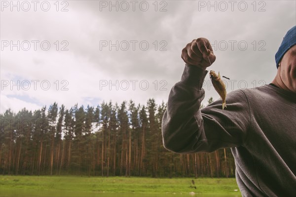 Fisherman holding small fish on hook