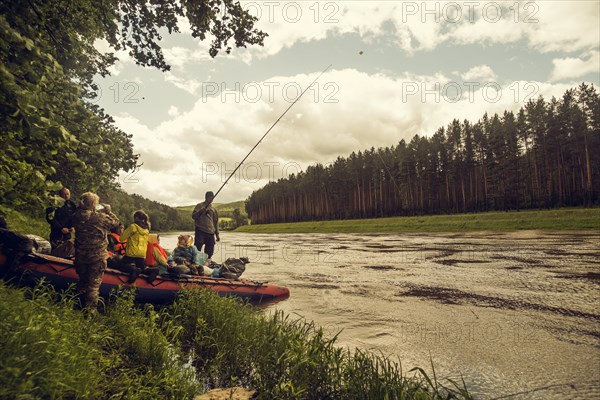 People with boat fishing on riverbank