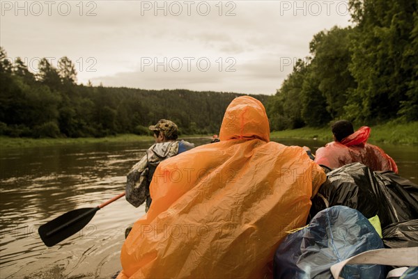 People wearing ponchos on boat in river