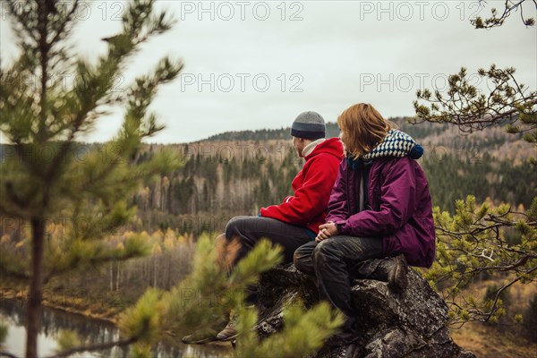 Friends sitting on rock on remote hillside