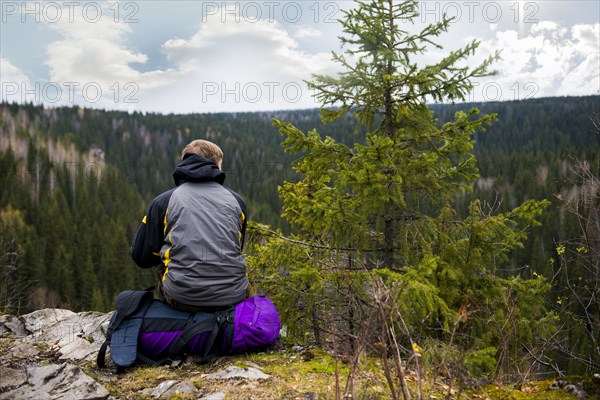 Caucasian hiker sitting on remote hilltop