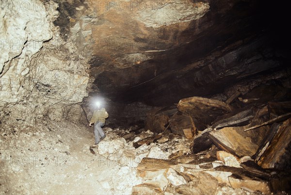 Caucasian hiker wearing headlamp in cave