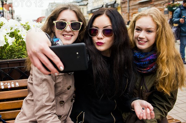 Caucasian women taking selfie on bench