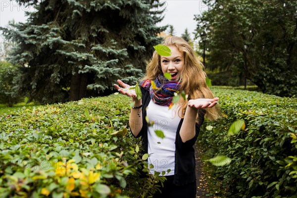 Caucasian woman tossing leaves in garden