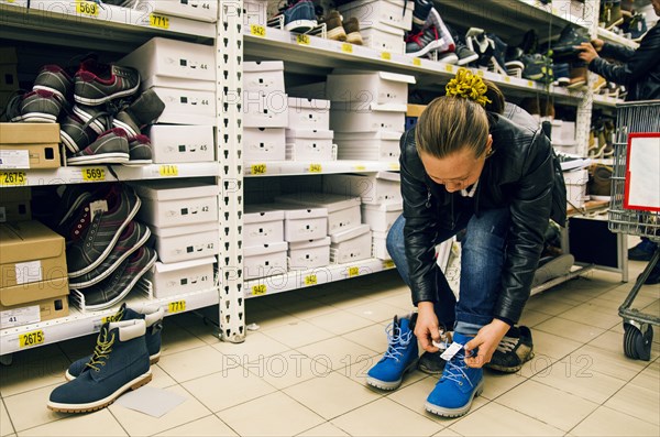 Caucasian woman trying on shoes in store