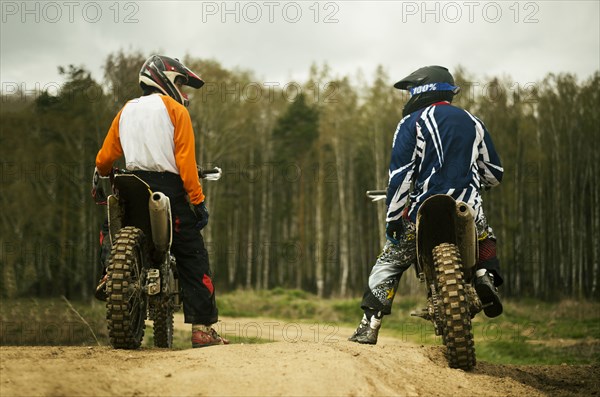 Caucasian men riding dirt bikes on road