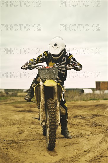 Caucasian man riding dirt bike in field