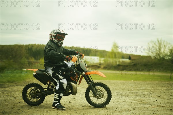 Caucasian man riding dirt bike in field