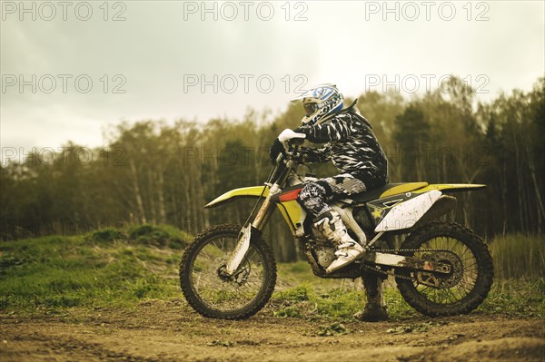 Caucasian man riding dirt bike in field