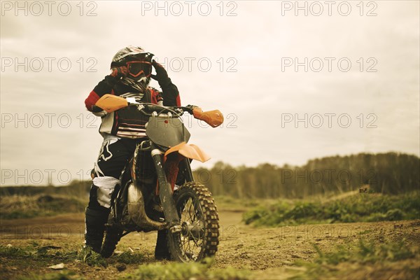 Caucasian man riding dirt bike in field