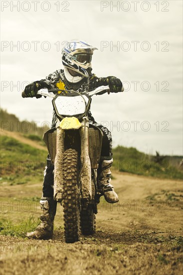 Caucasian man riding dirt bike in field