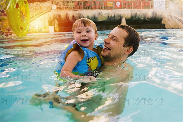 Caucasian father and daughter swimming in pool