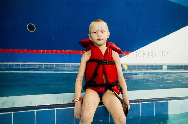 Caucasian boy wearing lifejacket at swimming pool