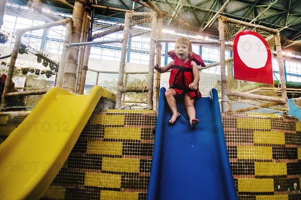 Caucasian girl riding slide at water park