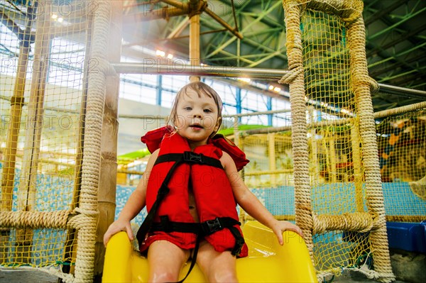 Caucasian girl riding slide at water park
