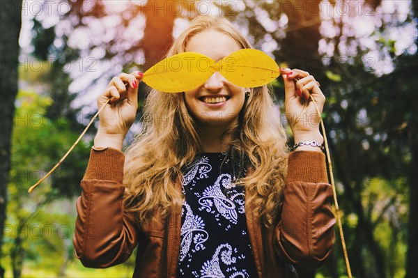 Caucasian woman playing with autumn leaves