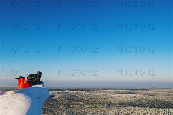 Hiker admiring view from snowy hilltop