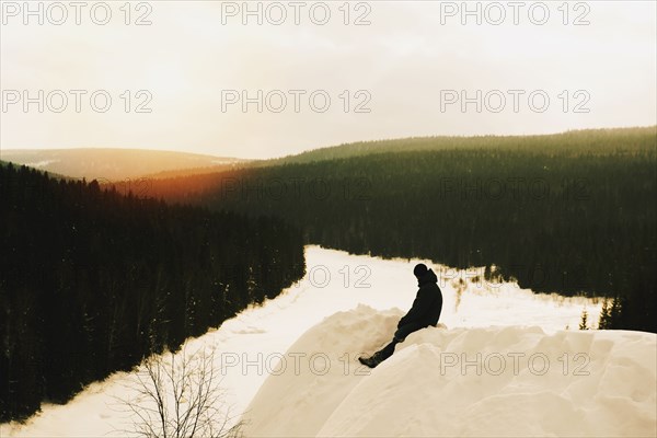 Caucasian hiker sitting on snowy mountain