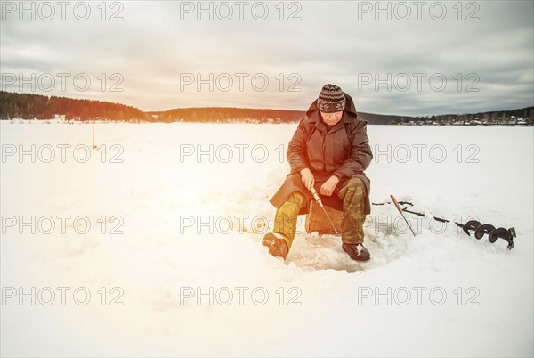 Man ice fishing in frozen lake