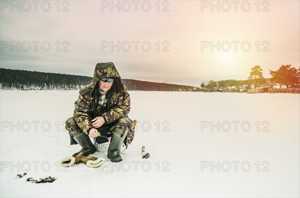 Man ice fishing in frozen lake