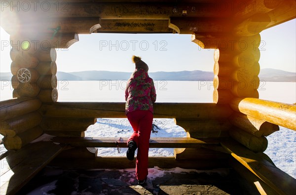 Woman admiring snow from lodge balcony in winter