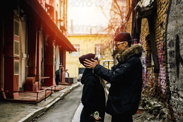 Man holding head of woman in urban alley