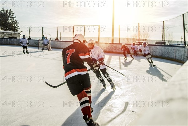 Caucasian boys playing ice hockey outdoors