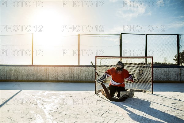 Caucasian boy playing goalie in ice hockey outdoors